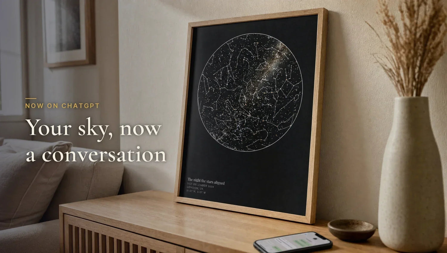 A framed Skylit Studio star map print in a living room with a phone showing a chat - design a star map by chatting on ChatGPT