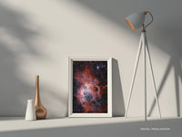 Space-themed deep sky print of NGC 604 nebula displayed in a white frame on a neutral shelf with ambient lighting – ideal astronomy wall art for contemporary homes by Skylit Studio.