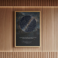 Personalized framed star map print in a natural wood brown frame, featuring a deep-space constellation design and the romantic quote 'The stars were just stars, the sky was just the sky, until you stood under it with me.' Custom astronomy wall art commemorating a special moment, perfect for anniversaries, weddings, or romantic gifts. Displayed in a warm, modern interior with wooden panelling and ambient lighting. Medium 50 x 70 cm framed star map poster.