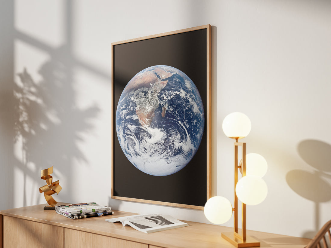 Framed The Blue Marble print by Skylit Studio on a sideboard in a bright living room