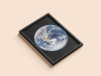The Blue Marble print in a black frame, flat lay