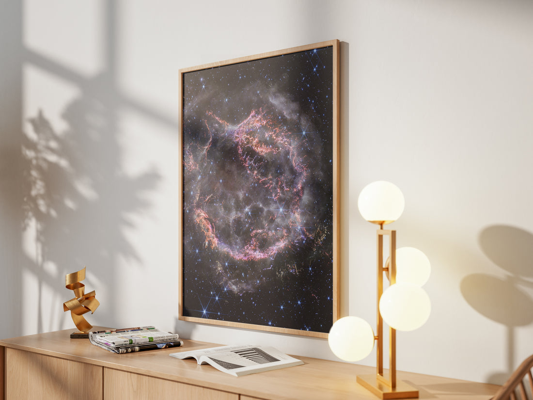 Framed Cassiopeia A print by Skylit Studio on a sideboard in a bright living room