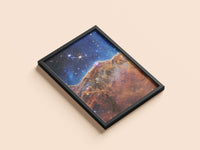 Cosmic Cliffs print in a black frame, flat lay