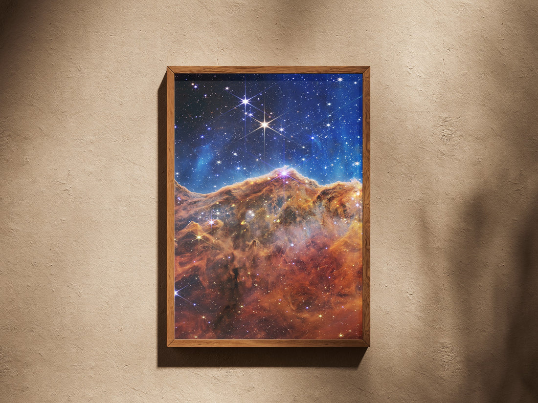Cosmic Cliffs print in a wooden frame on a plaster wall
