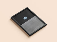 Earth on the Horizon print in a black frame, flat lay