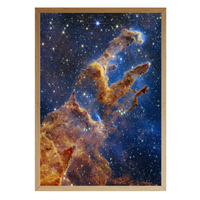 Framed print of the Pillars of Creation nebula in deep space, showing towering columns of gas and stardust surrounded by a sparkling star field, set against a white background.