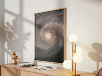 Framed Whirlpool Galaxy print by Skylit Studio on a sideboard in a bright living room