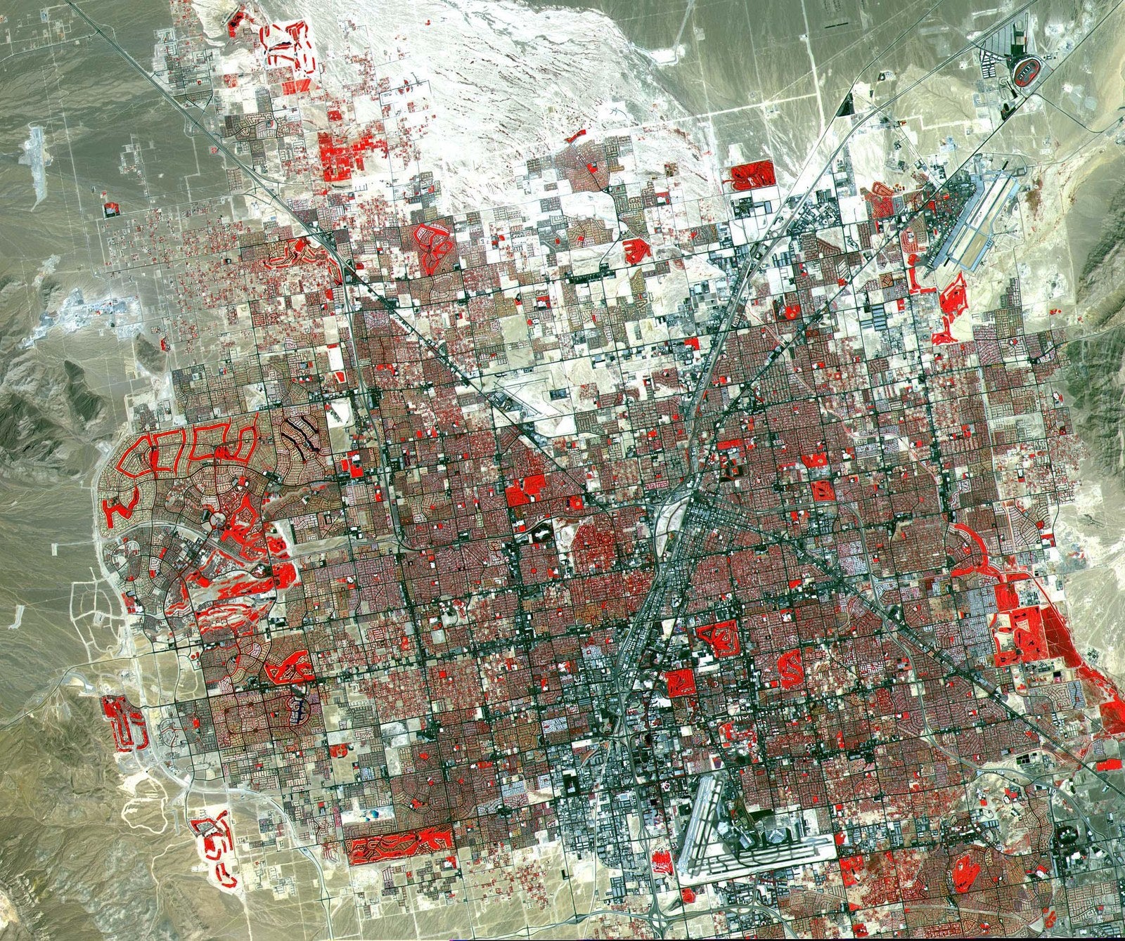 False-colour satellite image of Las Vegas showing the urban grid in grey, irrigated parks in red, and surrounding Mojave Desert in tan